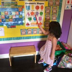 girl pointing to shapes in a classroom